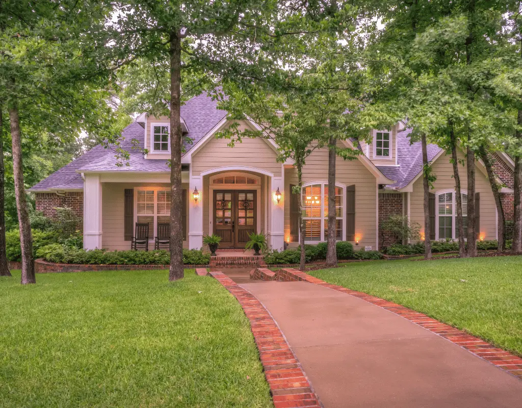 Craftsman-style home with a brick-edged front walkway, green lawn and mature shade trees